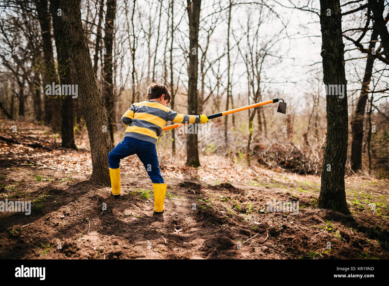 Boy in a garden digging soil with a hoe Stock Photo