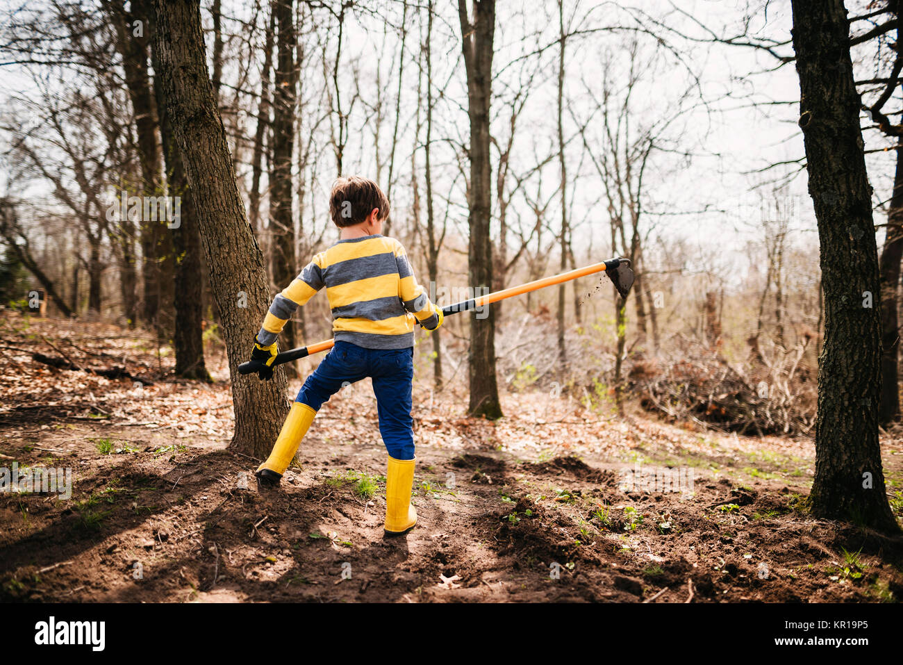 Boy in a garden digging soil with a hoe Stock Photo