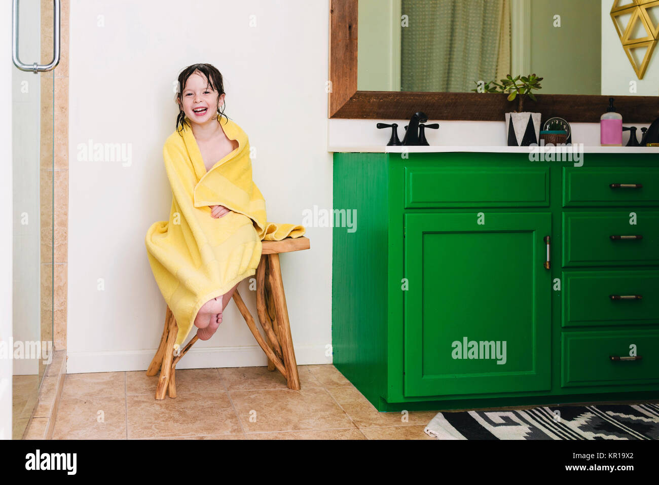 Girl sitting in bathroom wrapped in a towel after a bath Stock Photo
