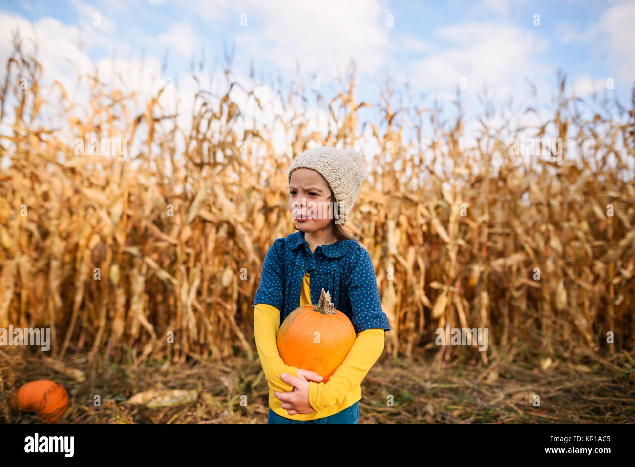 Girl standing in a pumpkin patch holding a pumpkin Stock Photo - Alamy