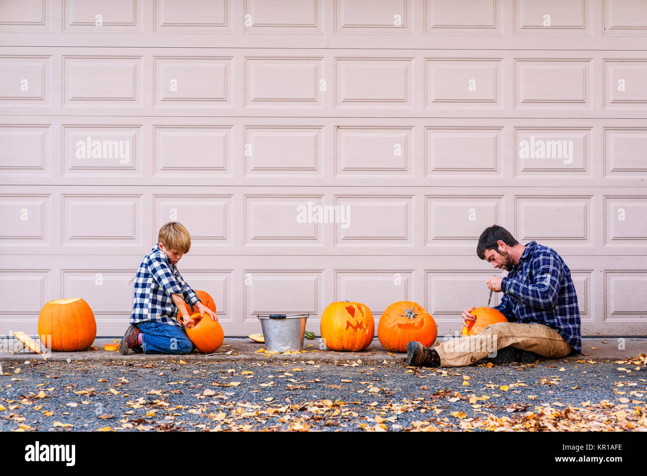 Father And Son Sitting By A Garage Door Carving Halloween