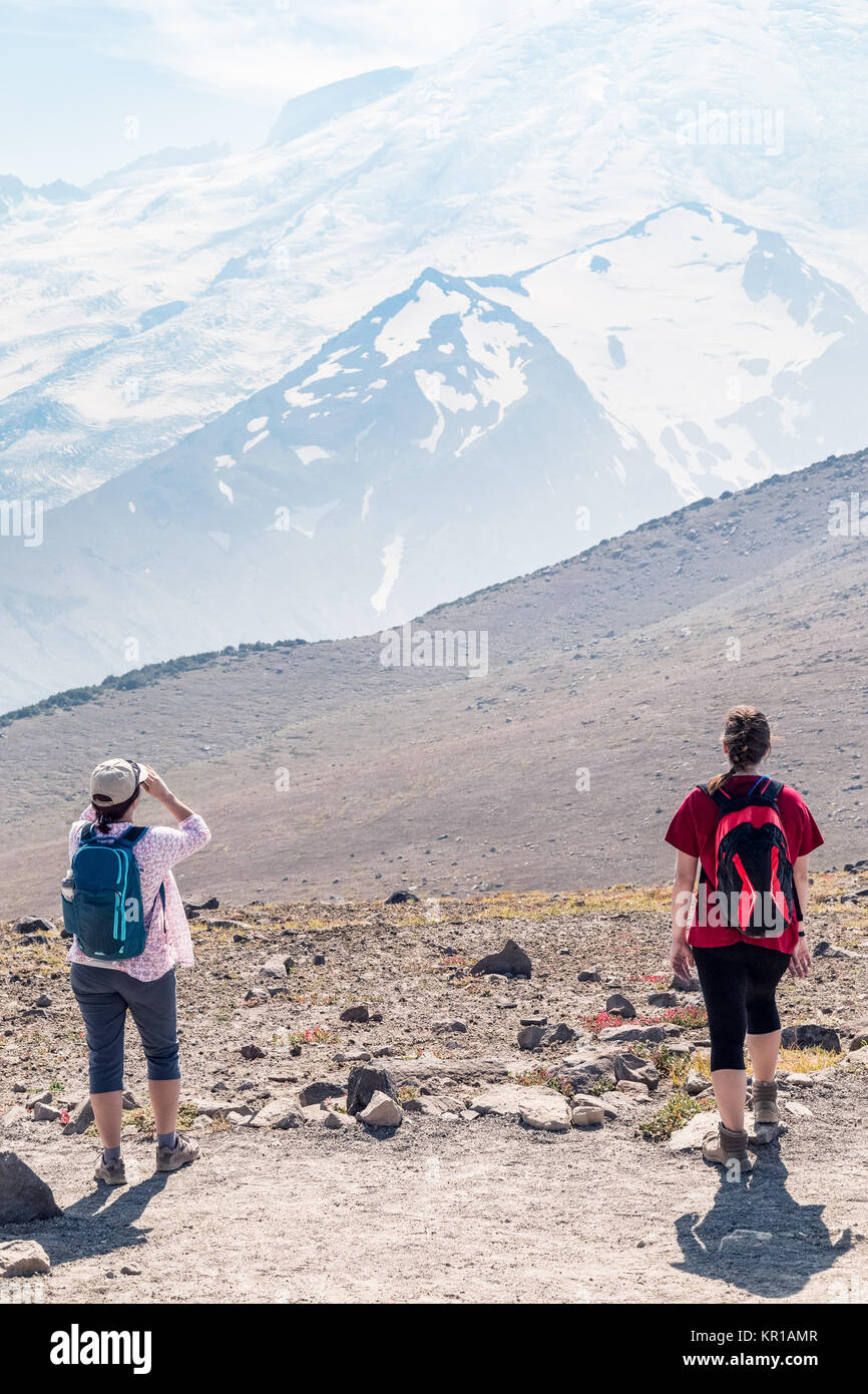 Two female hikers standing on an alpine trail, Mt Rainier, Washington, United States Stock Photo
