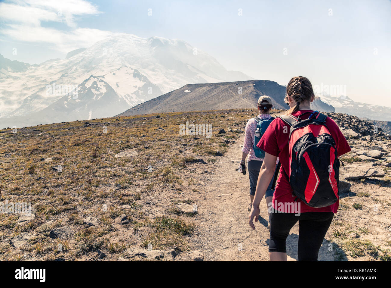 Two women hiking along an alpine trail, Mt Rainier, Washington, United States Stock Photo