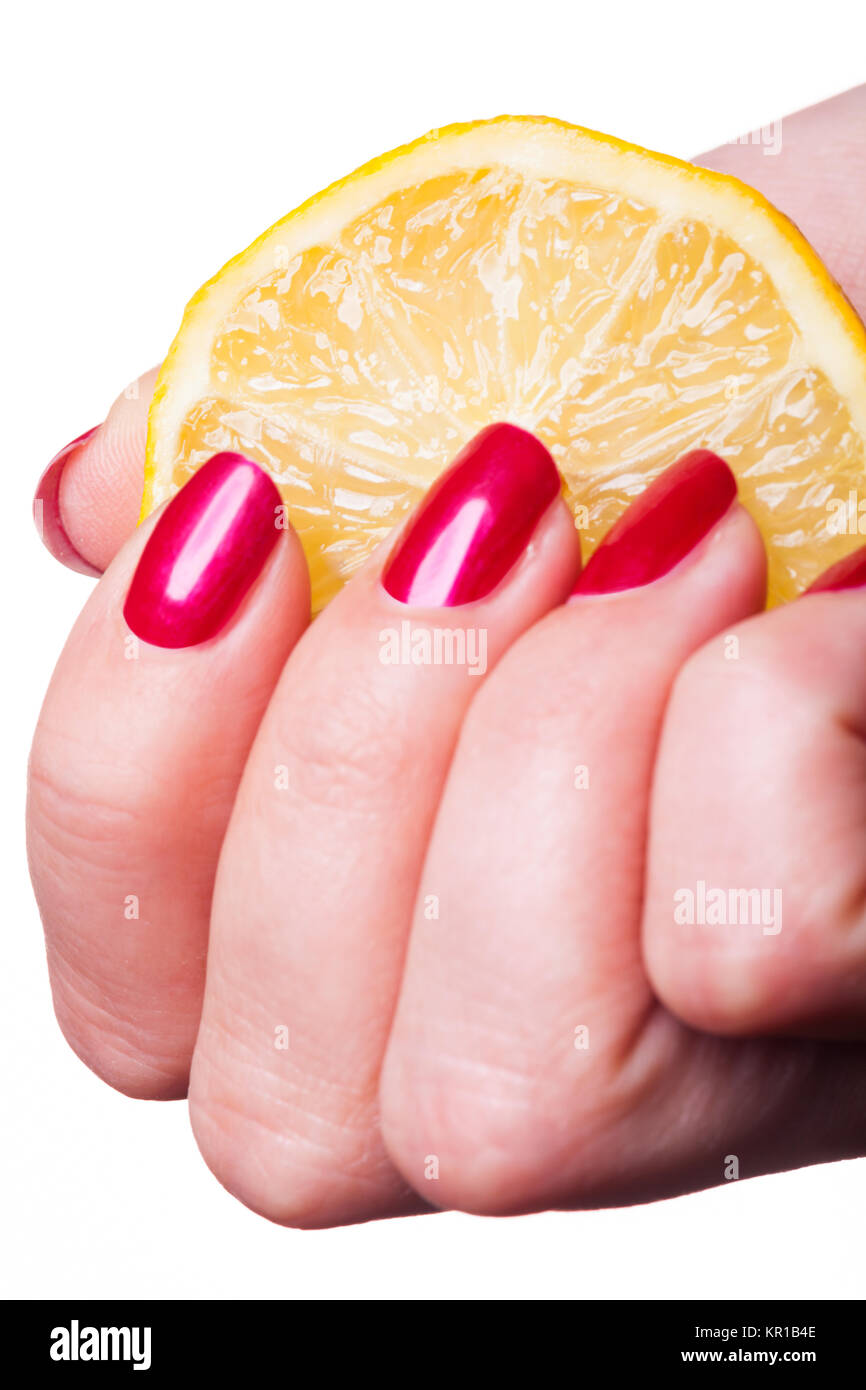 Hand mit perfekt lackierten roten Fingernägeln zerdrückt Eine Zitrone auf weißem Hintergund Stock Photo