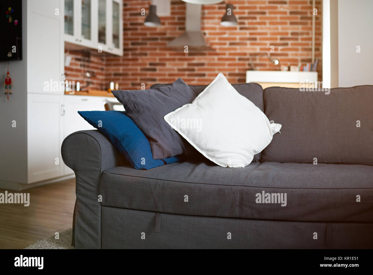 Gray sofa with kitchen on background with red brick wall Stock Photo