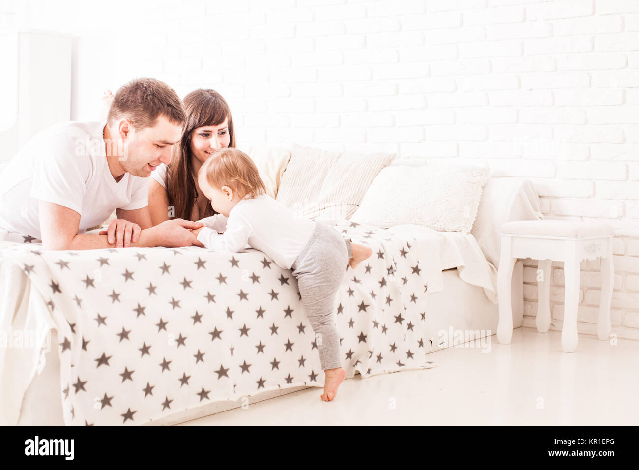 Parents teach the child to climb on the bed Stock Photo Alamy