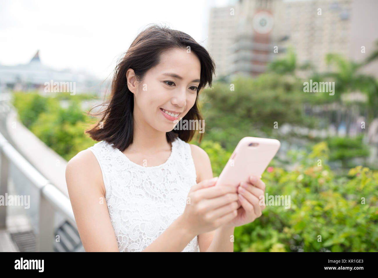 Woman use of smart phone with hong kong clock tower Stock Photo - Alamy