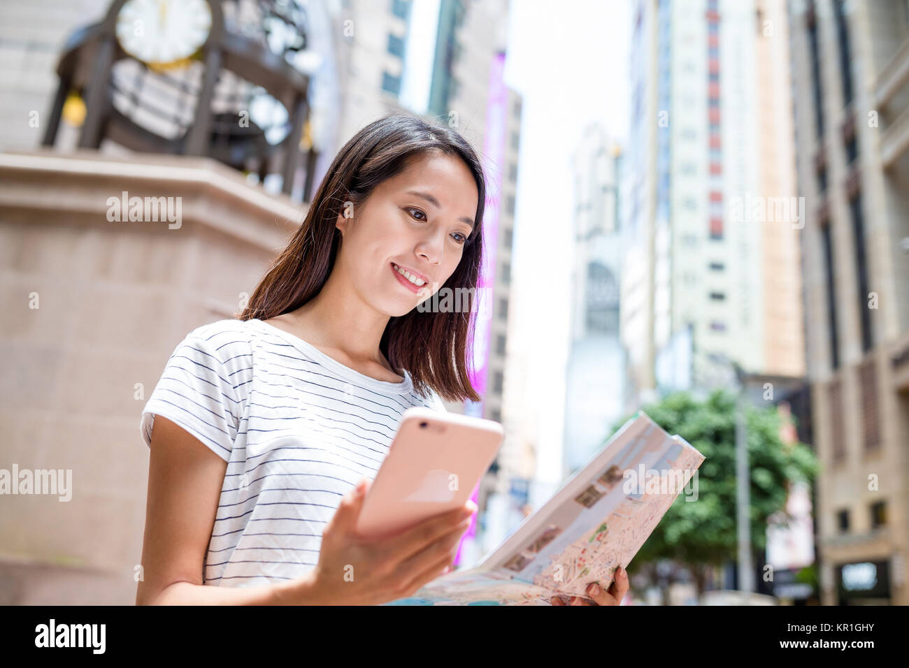 Woman looking at city map with mobile phone in Hong Kong city Stock ...