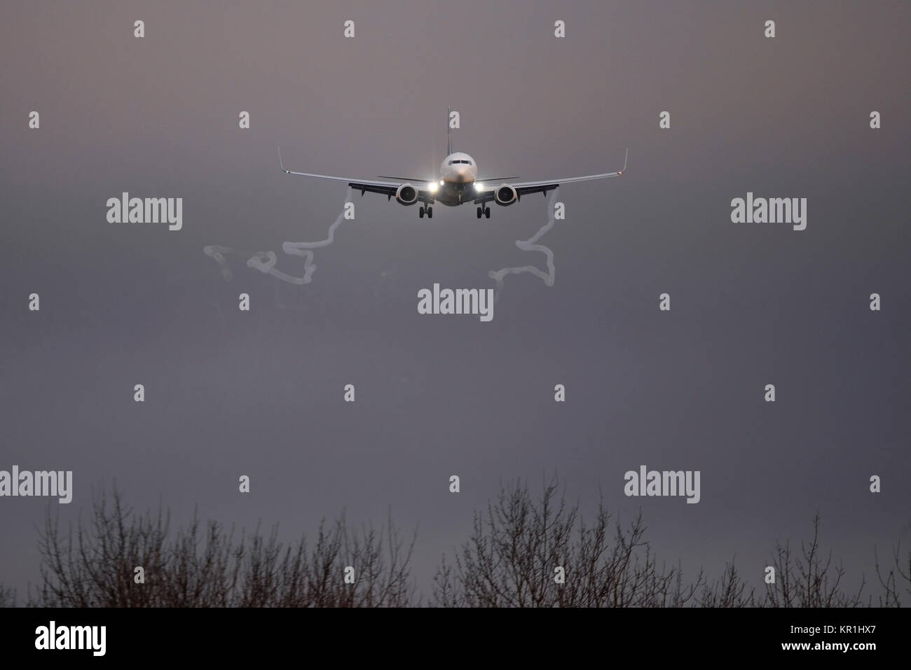Ryanair Boeing 737 airliner jet plane landing at London Stansted Airport at dusk with landing lights shining bright and vortex vortices trailing Stock Photo