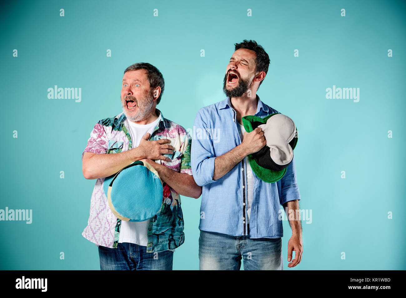 The two football fans singing the national anthem over blue Stock Photo