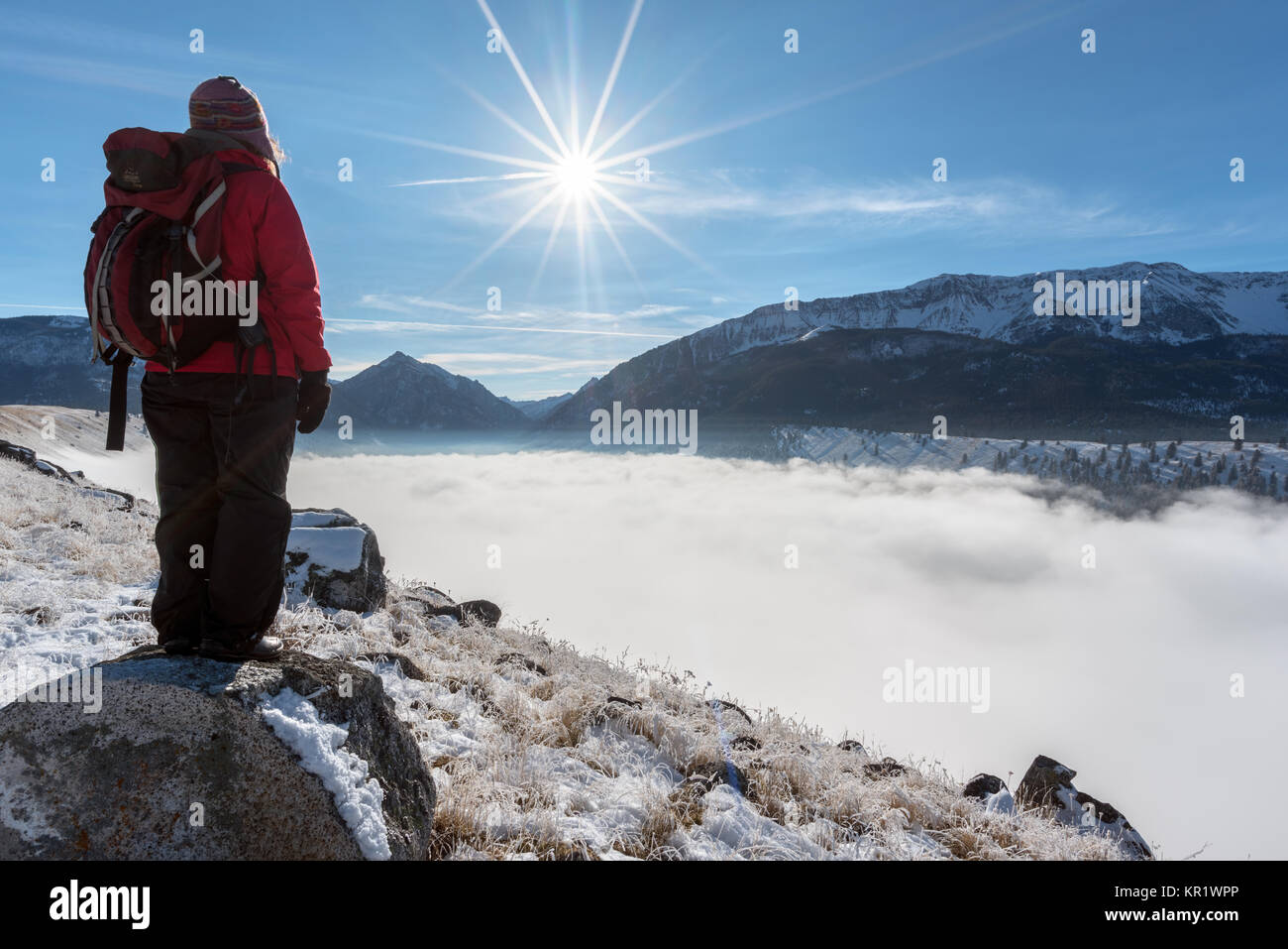 Hiker gazing on Wallowa Lake's east moraine gazing out at the Wallowa Mountains and fog filling the lake basin, Oregon. Stock Photo