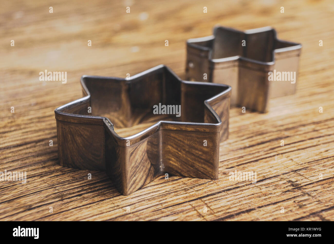Two star shaped pastry cutters lying on a old wooden table. These pastry cutters are used to make traditional christmas cookies Stock Photo