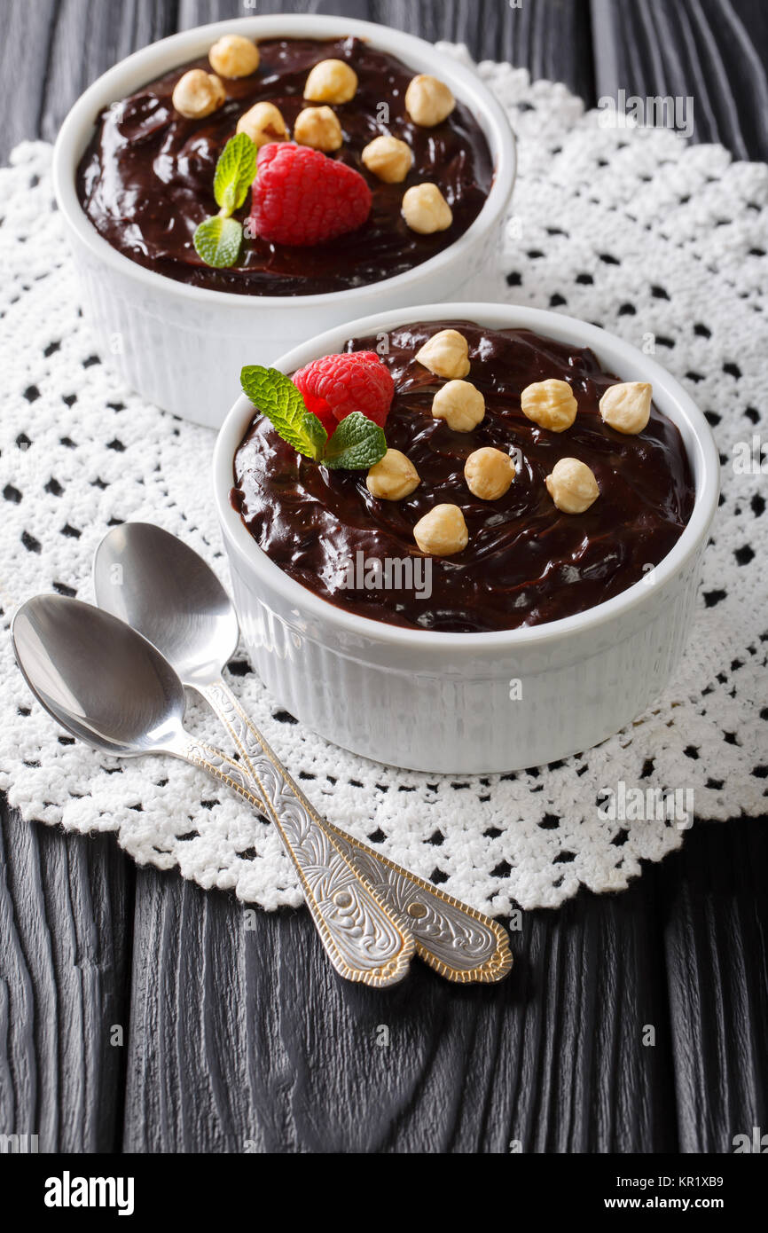 chocolate pudding is decorated with hazelnuts, mint and raspberries close-up on the table. vertical Stock Photo