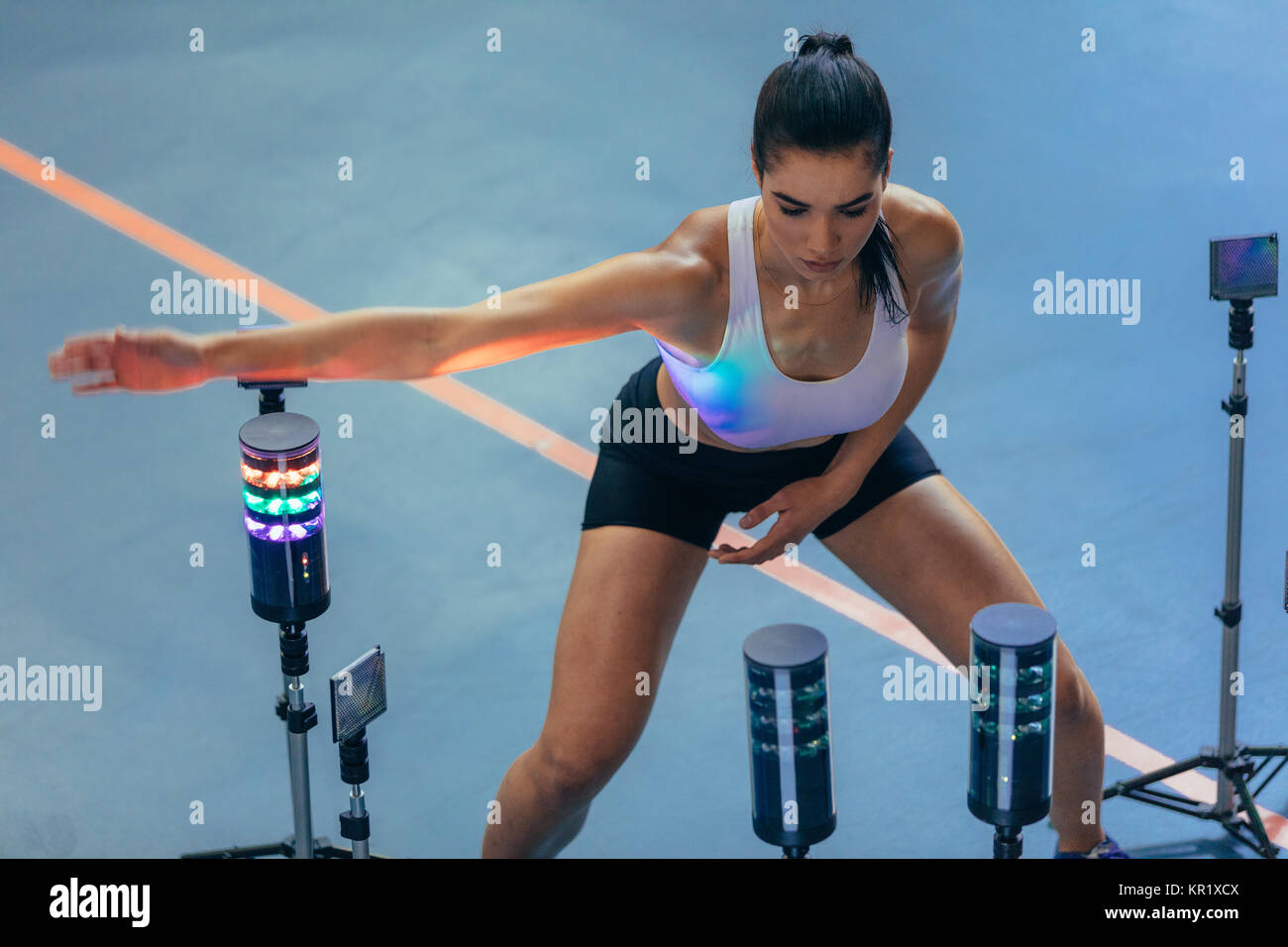Sportswoman exercising with lights around, reaction training session at gym. Female athlete