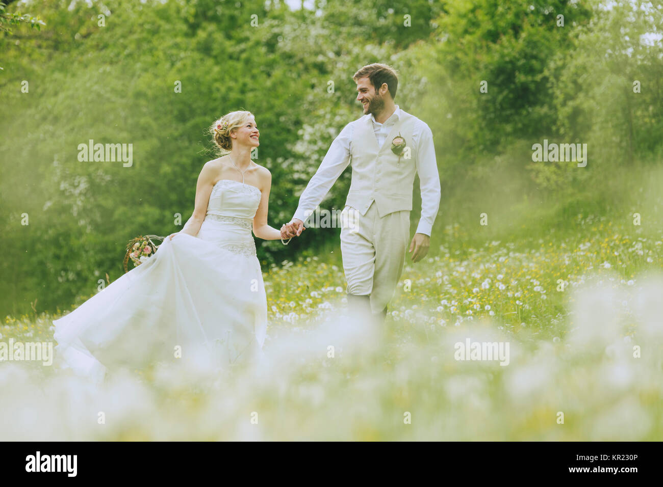 Bride and groom walking together holding hands on a gorgeous blooming ...
