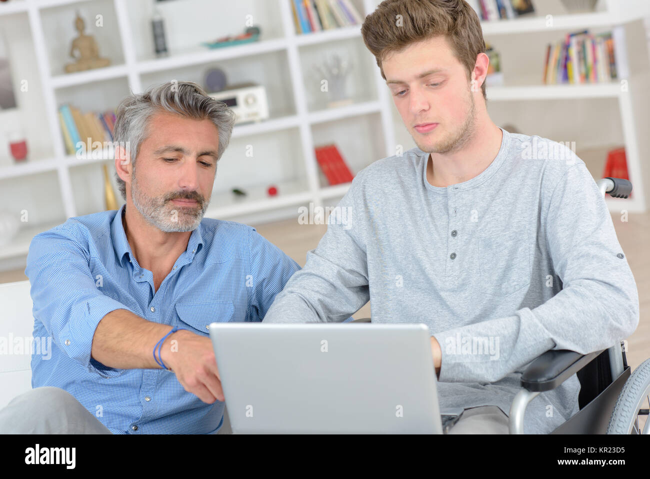 Man helping boy in wheelchair to use a computer Stock Photo - Alamy
