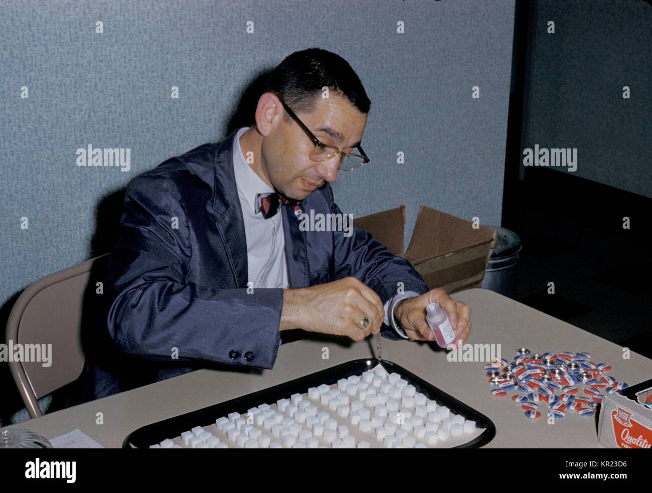 A healthcare worker is dropping oral poliovirus vaccine on sugar cubes prior to immunization administration, 1961. A person is considered to be fully immunized if he or she has received a primary series of at least three doses of inactivated poliovirus vaccine (IPV), live oral poliovirus (OPV), or any combination of IPV and OPV. Image courtesy CDC. Stock Photo