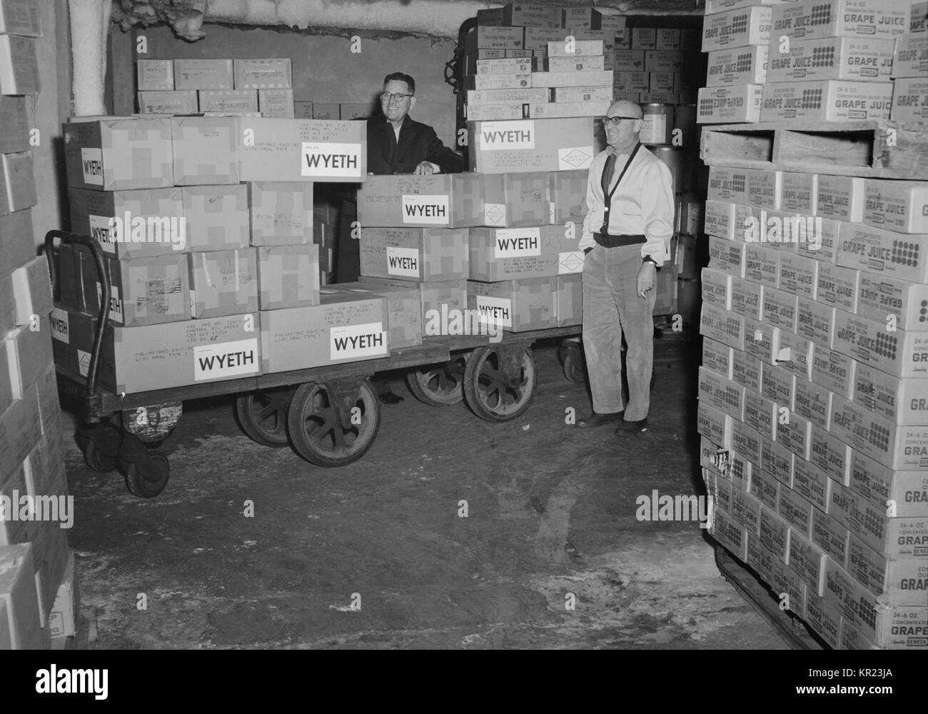 Two workers stand beside a cart loaded with boxes containing poliovirus vaccine, 1963. In the early 1950's, there were more than 20, 000 cases of polio each year. After polio vaccination began in 1955, cases dropped significantly. By 1960, the number of cases dropped to about 3, 000, and by 1979 there were only about 10. Image courtesy CDC/Mr. Stafford Smith. Stock Photo