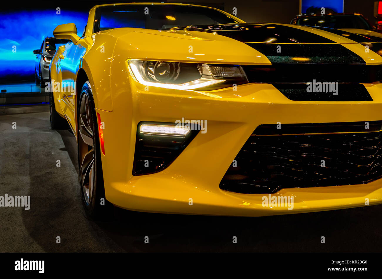 Modern yellow sports car with lighted headlights on the car show Stock Photo