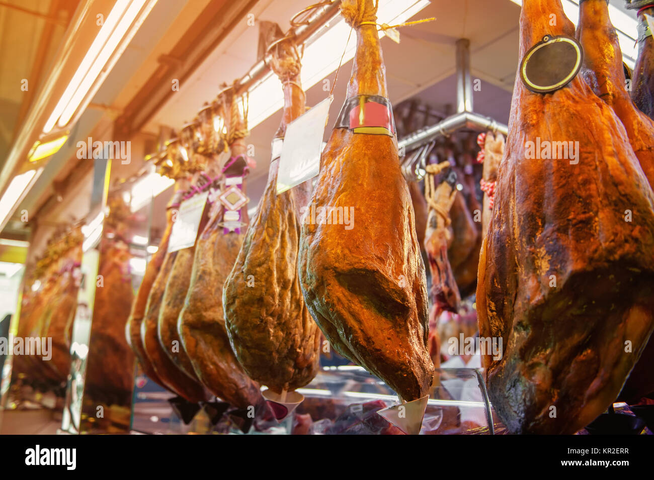Spanish ham, whole large pieces hanging on hooks on the market Stock