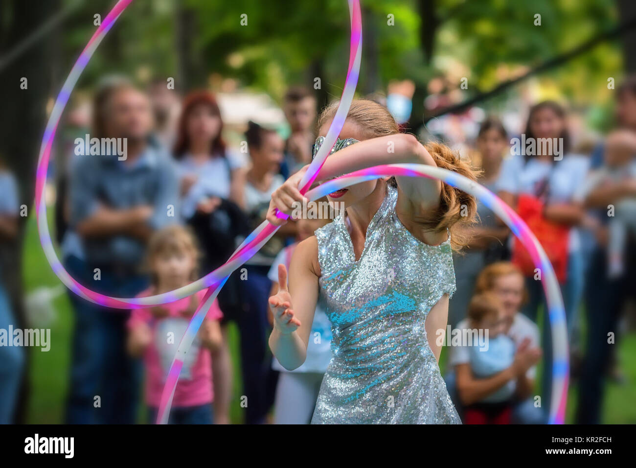 Girl in beautiful dress performs with hula hoops Stock Photo