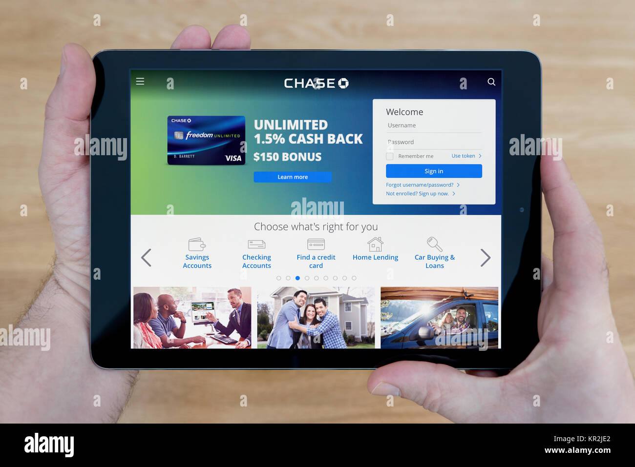 A man looks at the Chase Bank website on his iPad tablet device, shot against a wooden table top background (Editorial use only) Stock Photo