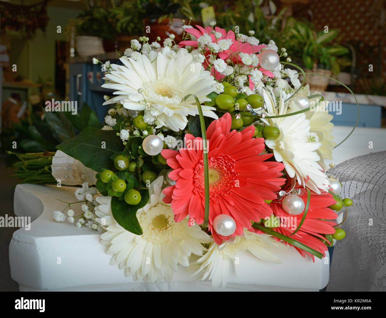 Photo of a festive, coral and white bridal bouquet with gerbera daisies, hydrangea, hypericum berries, baby's breath, grass loops and big fun pearls. Stock Photo