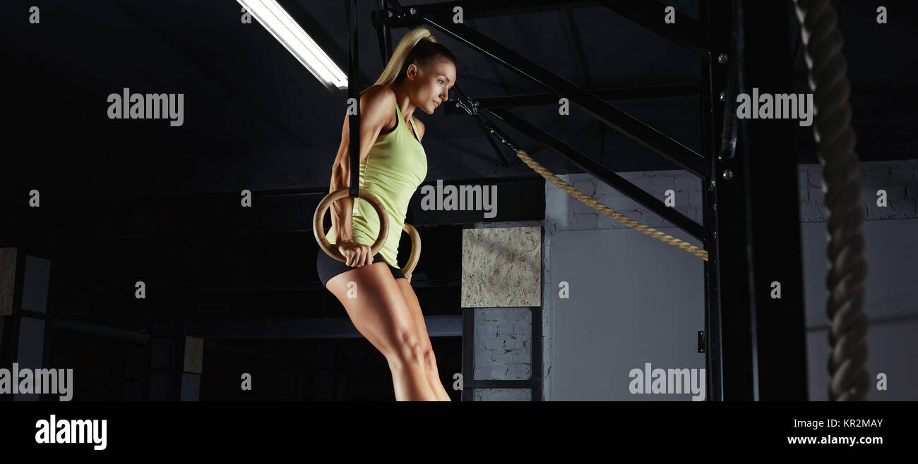 Low angle shot of a sportswoman doing ring dips at the crossfit gym