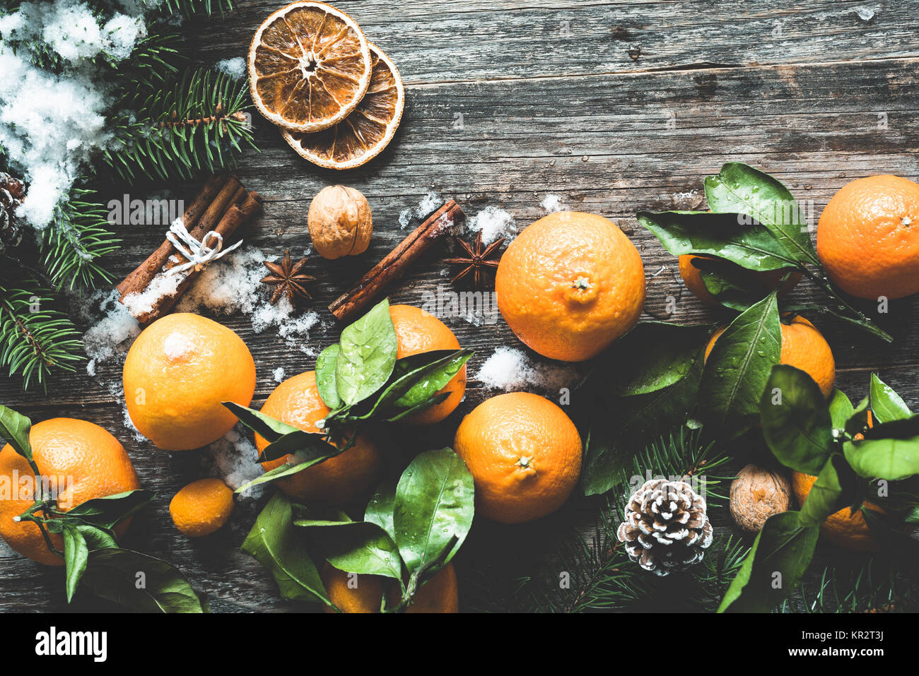 Traditional Christmas background with fir tree, tangerines, cinnamon and natural snow on wooden background. Top view, toned image Stock Photo