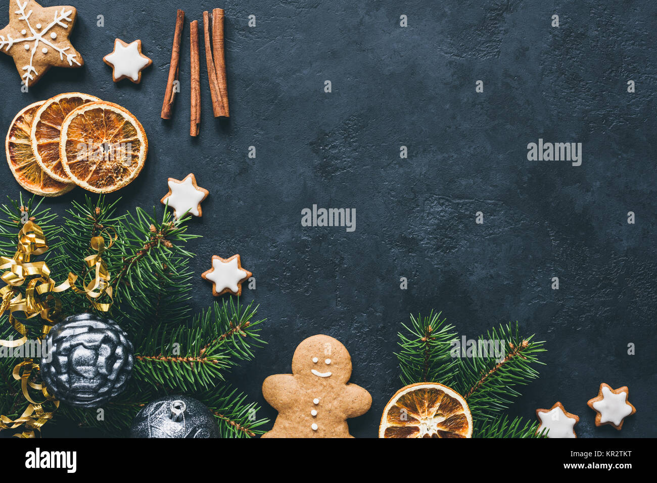 Christmas background with fir tree branch, gingerbread cookies, spices and dried orange rings. Top view and copy space for text Stock Photo