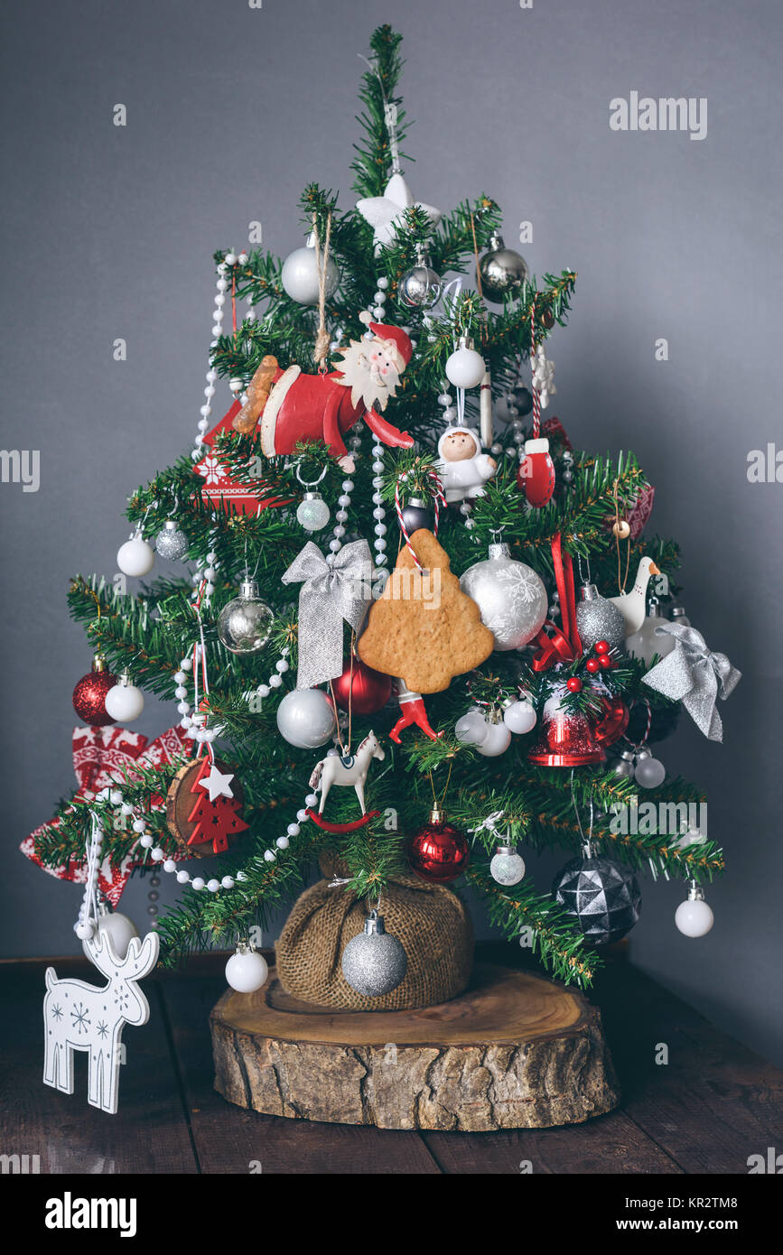 Small Christmas tree decorated with toys on wooden timber. Vertical composition Stock Photo