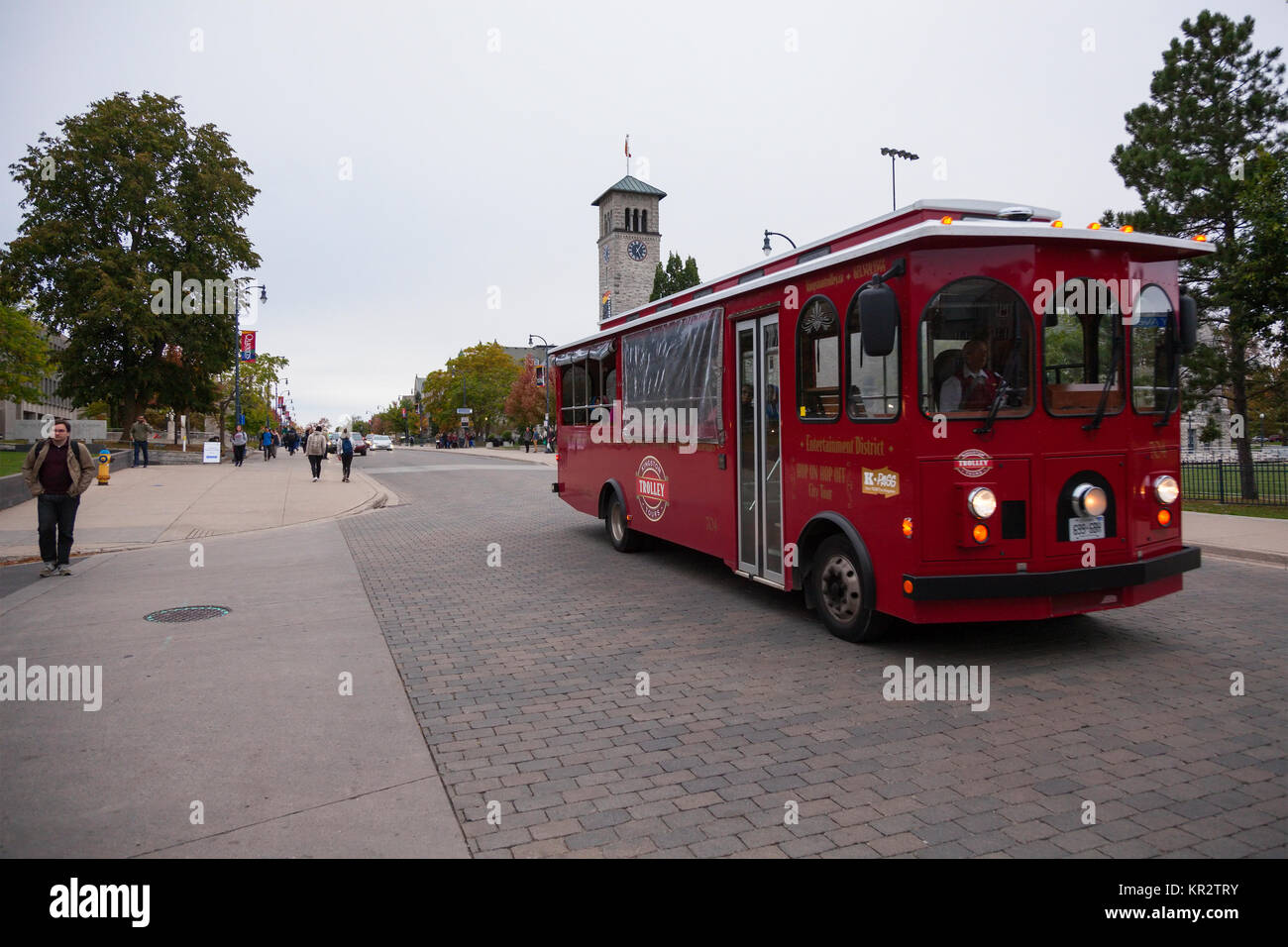 A Kingston City Tour Trolley is a Hop on Hop Off bus passing through Queen's University along University Avenue at Kingston in Kingston, Ontario. Stock Photo