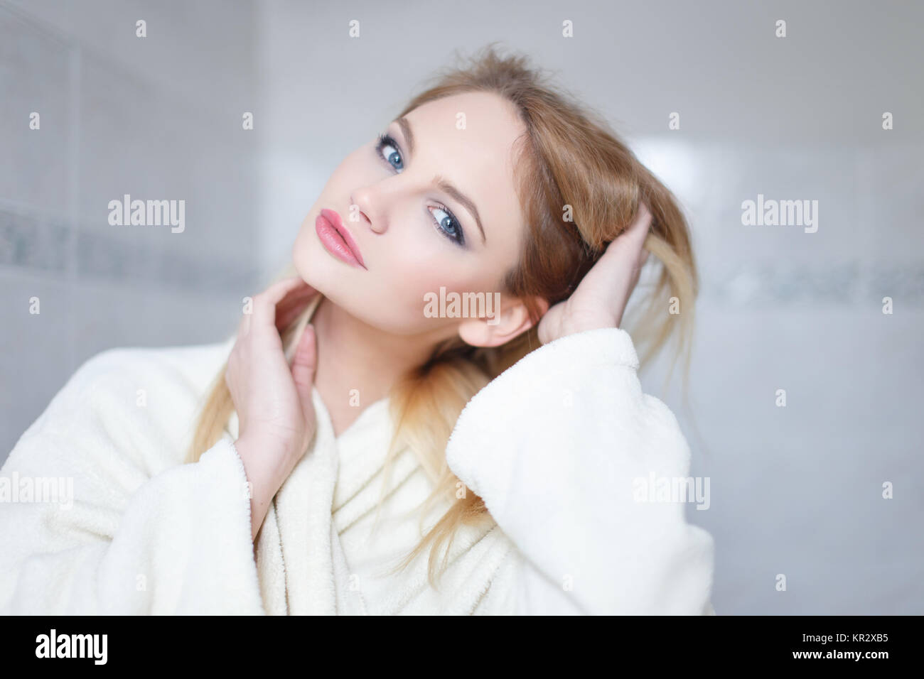 Young blonde woman in bathrobe portrait, posing in bathroom Stock Photo