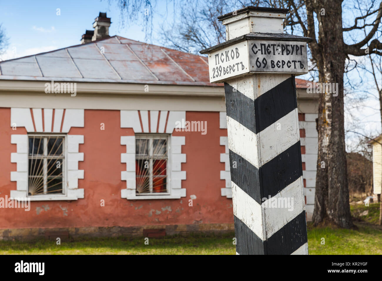 Retro stylized wooden milepost in Russian countryside. Text in Russian means distance to Pskov and St.Petersburg in versts Stock Photo