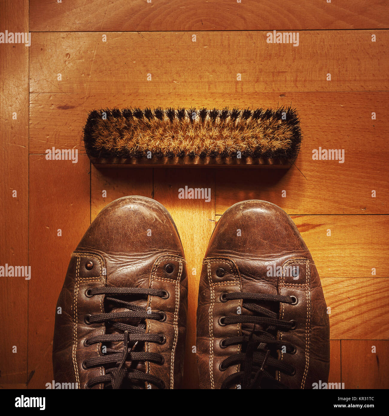 Closeup view of old dirty and used leather shoes on parquet with brush for cleaning. Stock Photo