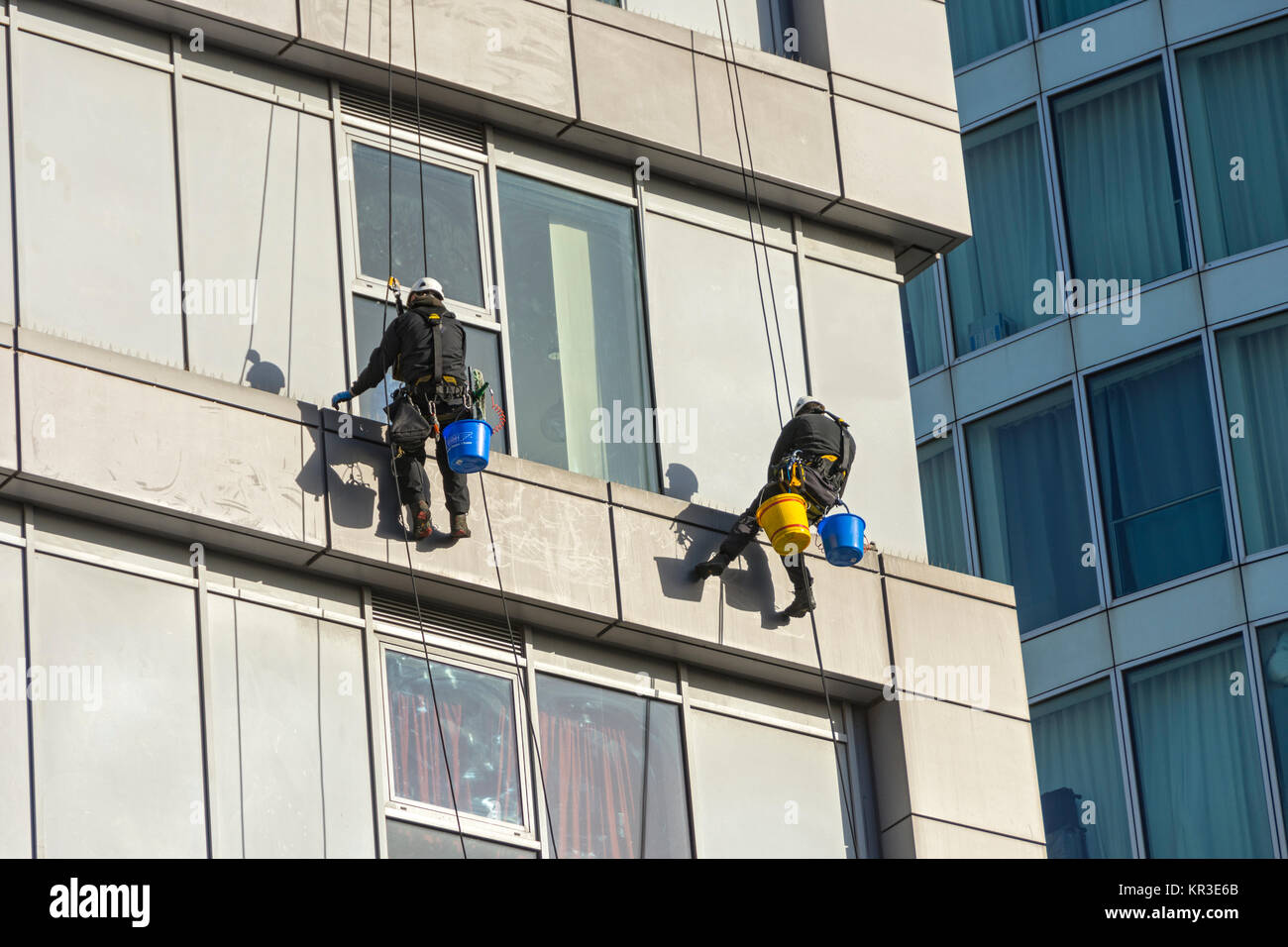 Two window cleaners using rope access techniques on a building near the