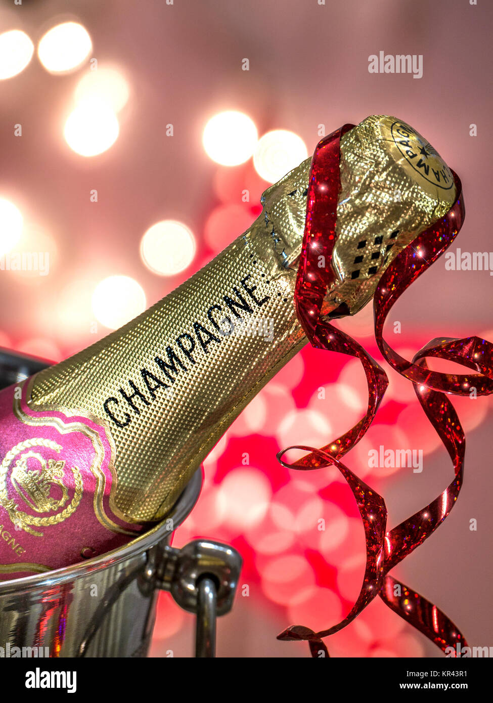 CHAMPAGNE PARTY LIGHTS Champagne bottle on ice in wine cooler with party streamer &  sparkling celebration lights Stock Photo