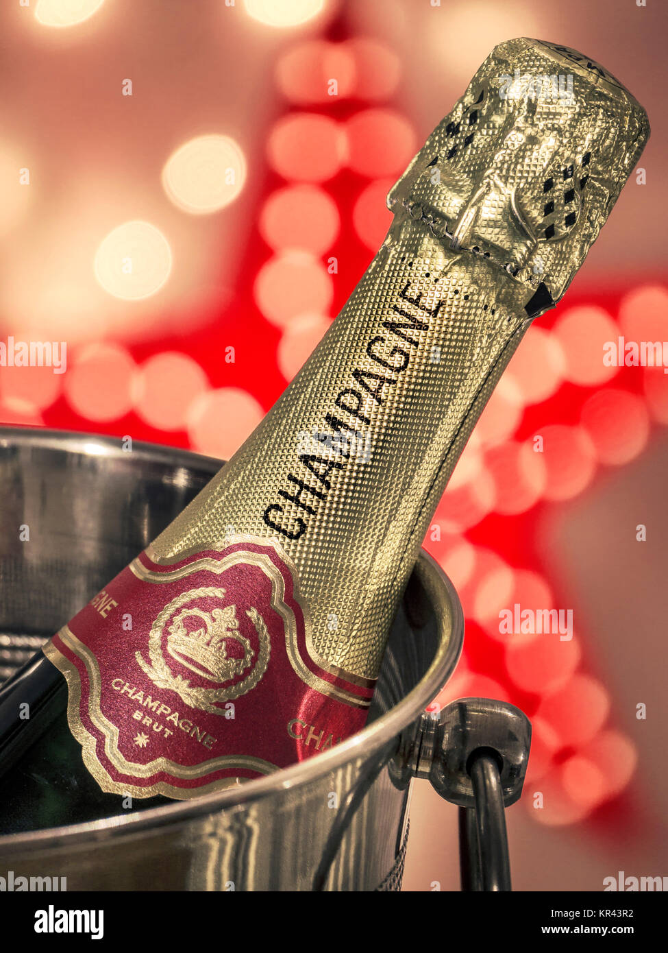 CHAMPAGNE CHRISTMAS PARTY LIGHTS Champagne bottle on ice in wine cooler with festive star and sparkling celebration lights Stock Photo