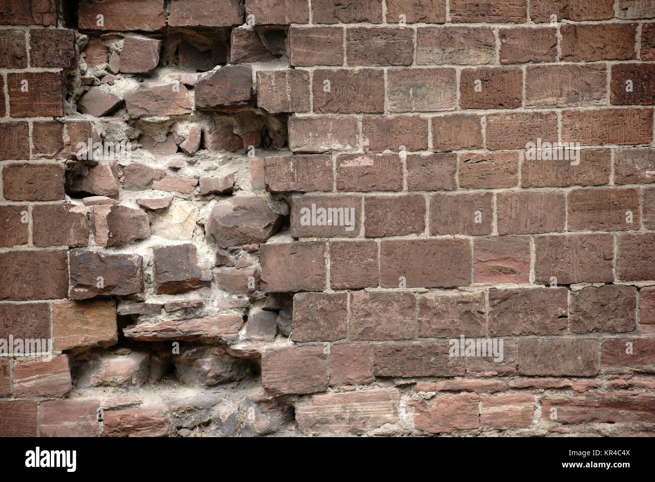 Eine Mauer aus markanten roten Steinen mit Beschädigungen und Löchern