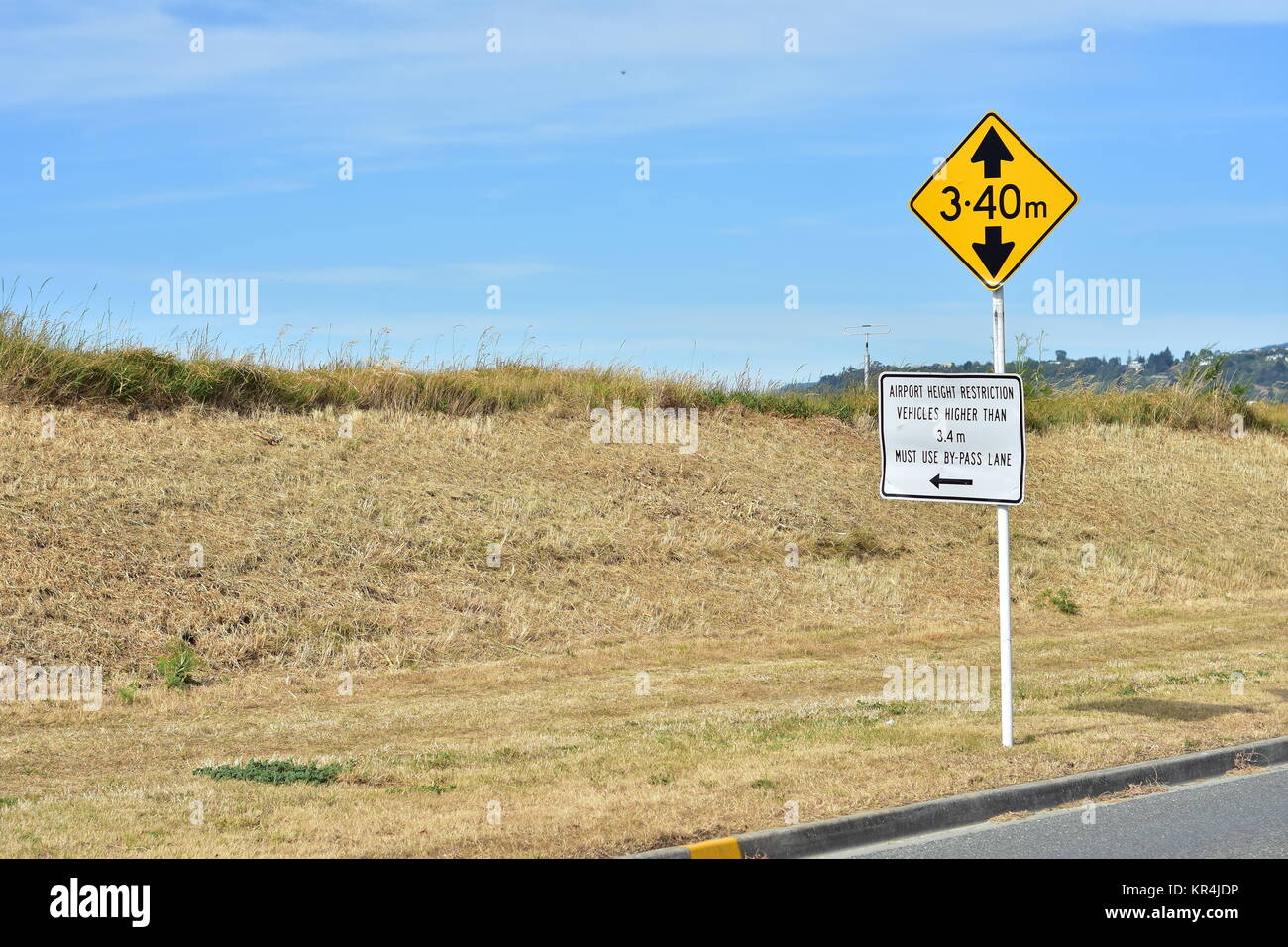 Bright yellow rectangular height restriction sign with bold black block letters on white metal pole. Stock Photo