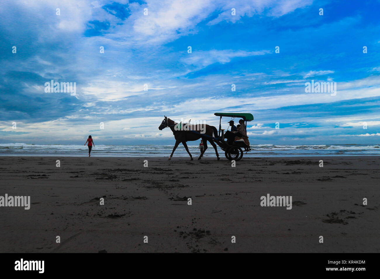 Tourist in a horse drawn carriage on Parangtritis Beach, Central Java, Indonesia. Stock Photo