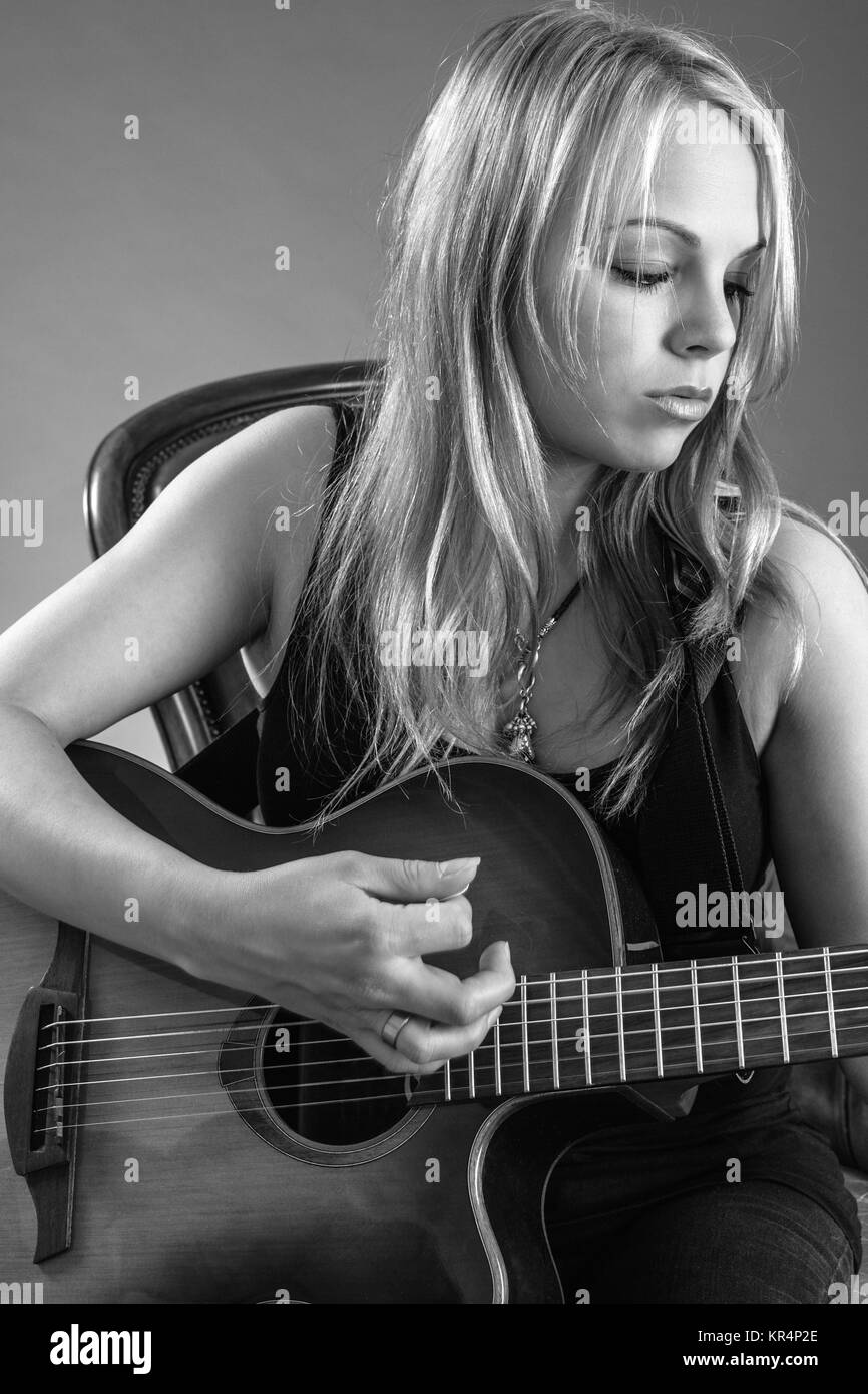 Photo of a beautiful blond female playing an acoustic guitar Stock