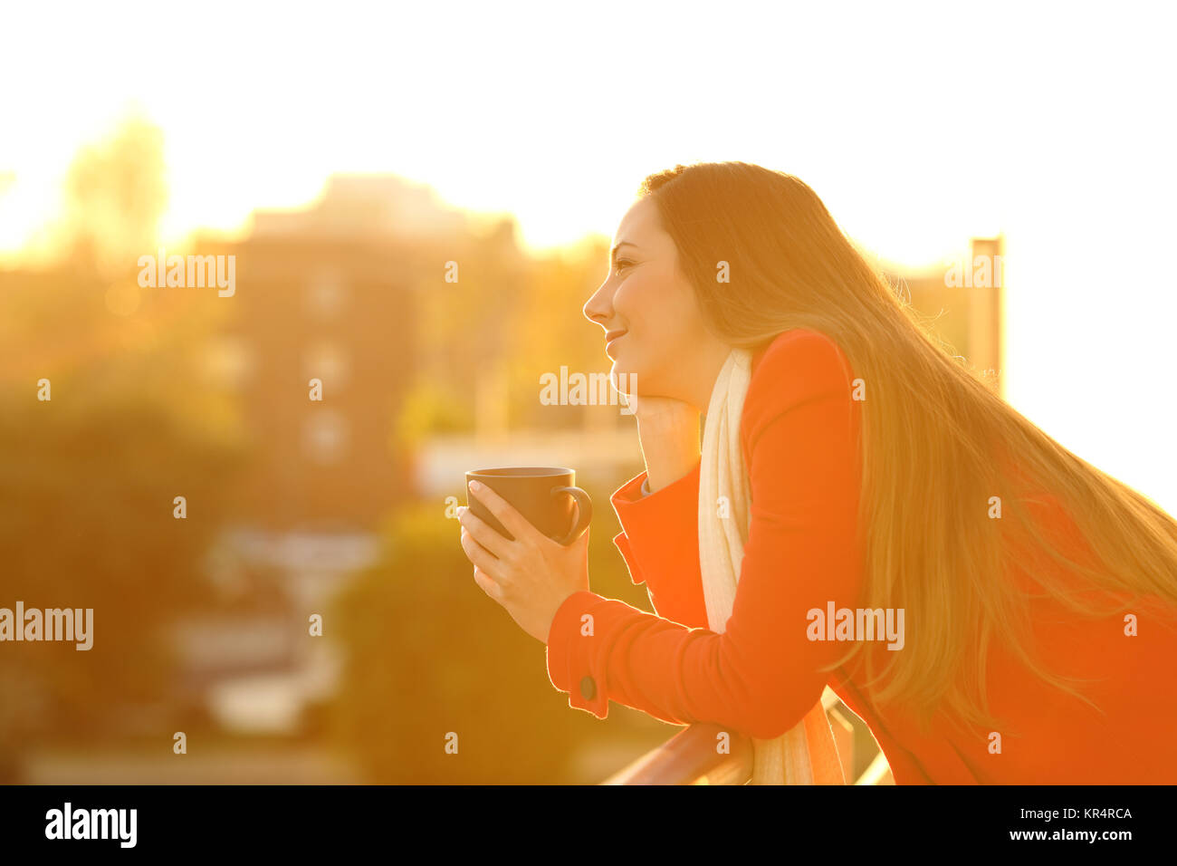 Side view portrait of a dreamer dreaming in a home balcony in winter at sunset Stock Photo