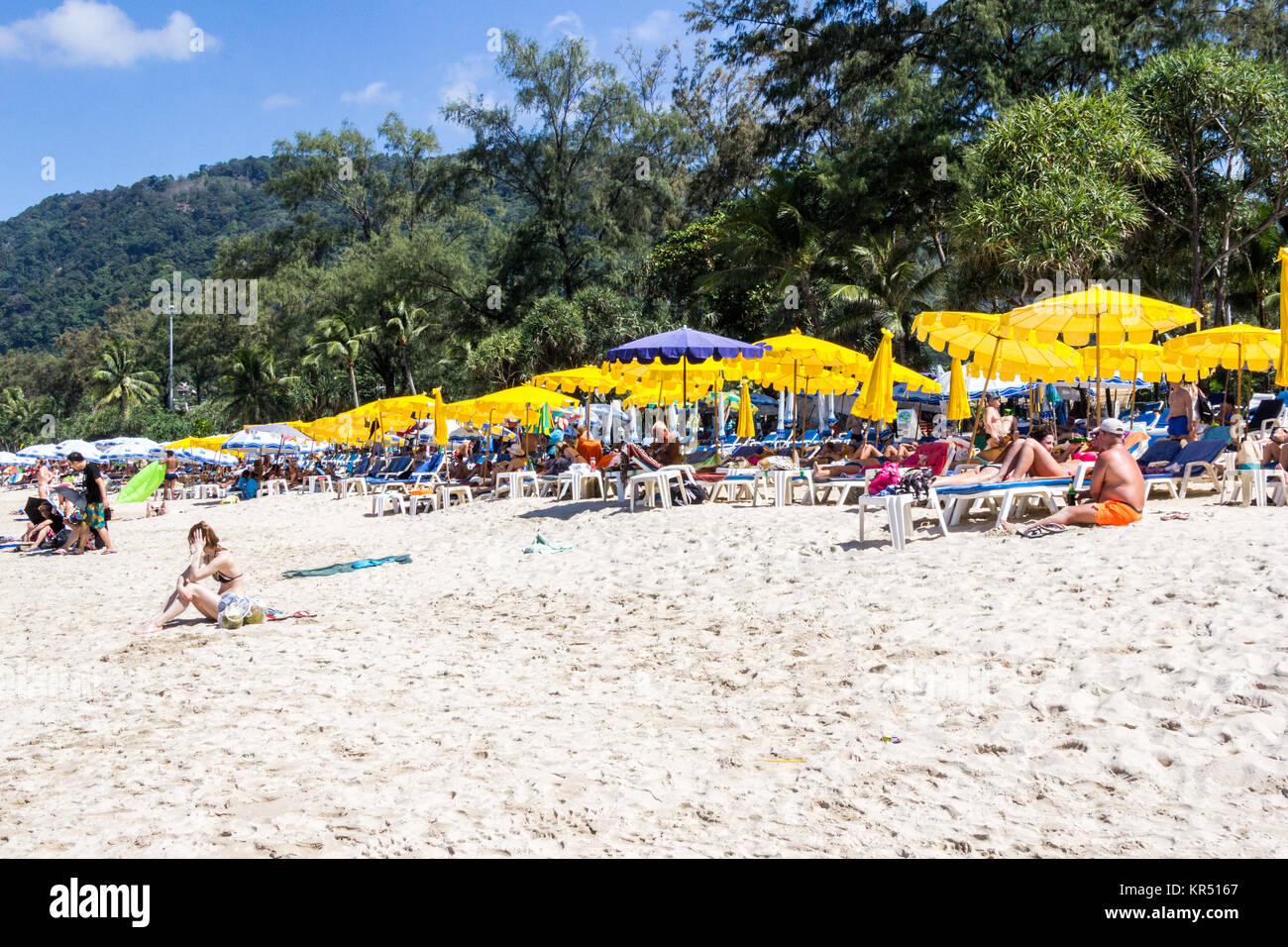 Tourists in reclining beach chairs and umbrellas on Patong beach during the high season, Phuket, Thailand Stock Photo