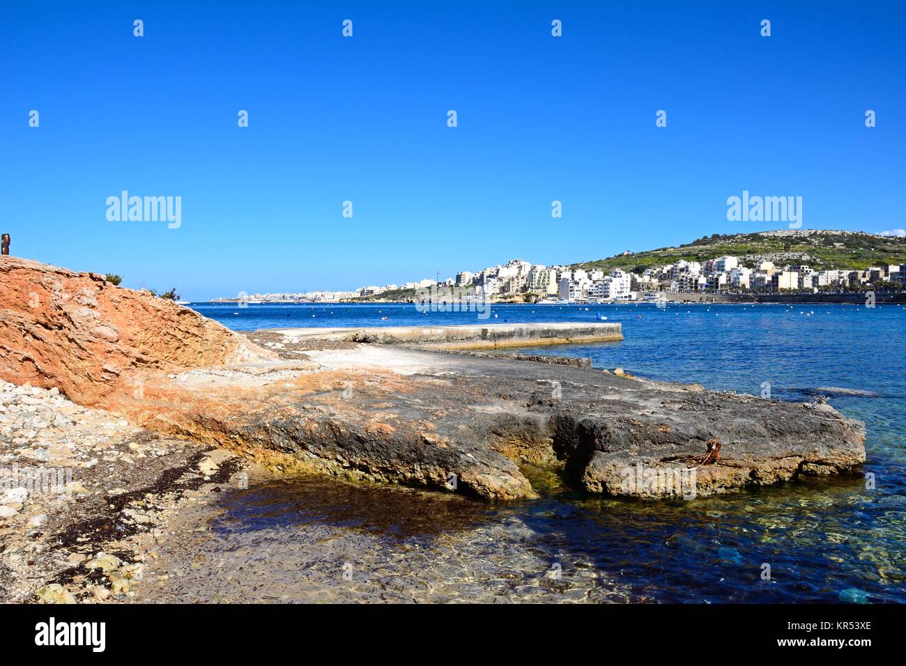 Rocky shoreline with views across the bay towards St Pauls Bay, San Pawl, Malta, Europe. Stock Photo