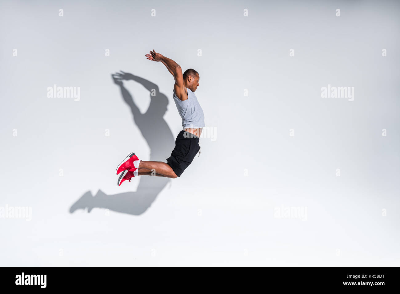 side view of young african american sportsman jumping on grey Stock ...