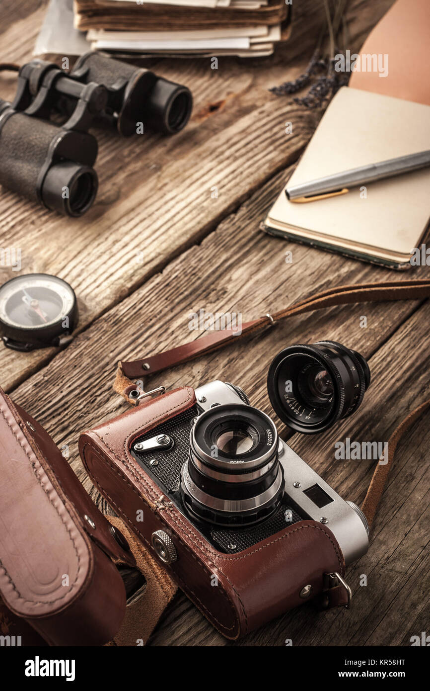 Camera with notebook and binoculars on the wooden table vertical Stock Photo