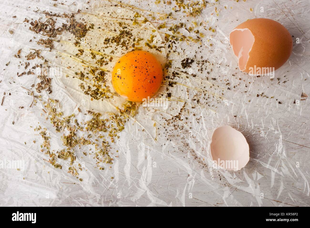 Broken egg with herbs mix on the white table Stock Photo