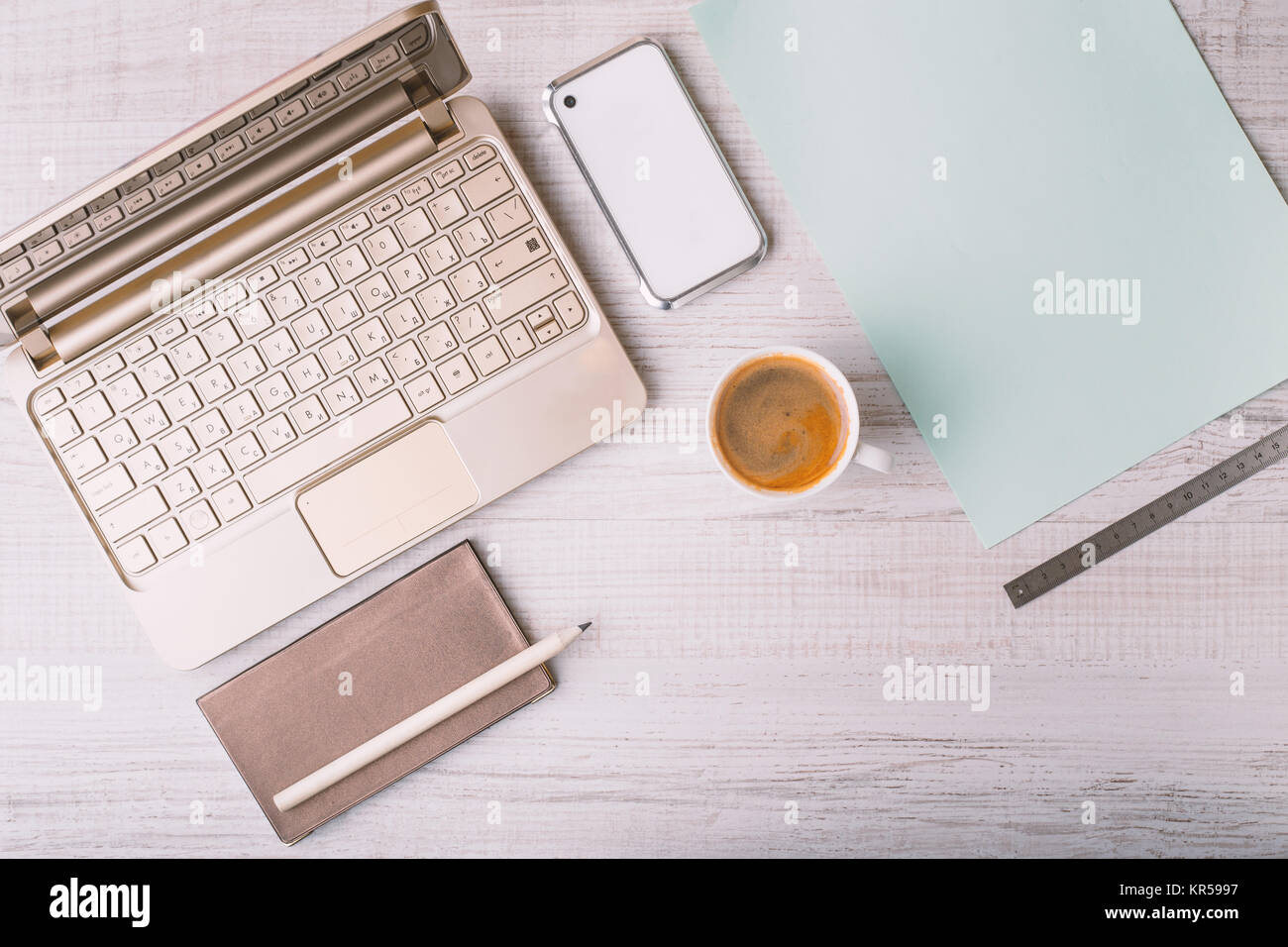 Laptop, phone and address book and a cup on a wooden table Stock Photo