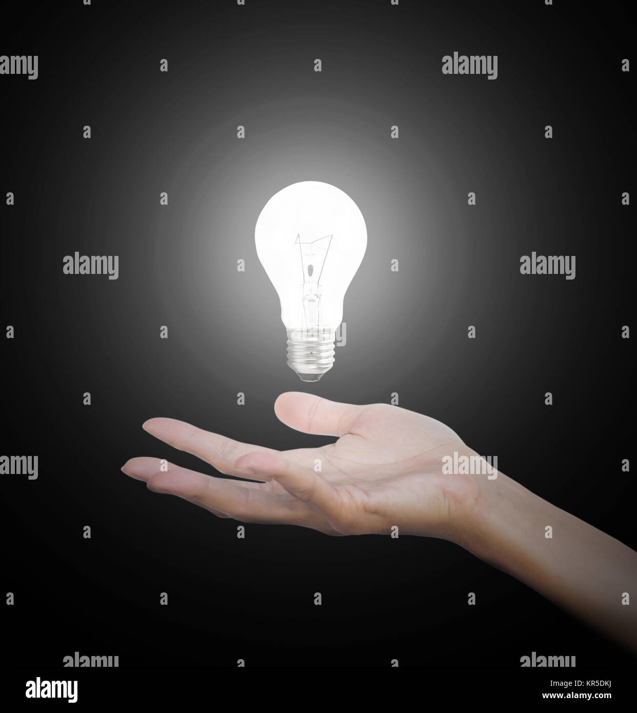 Hand gesture holding floating light bulb with light on dark background. Conceptual thinking new idea. Concept idea. Stock Photo